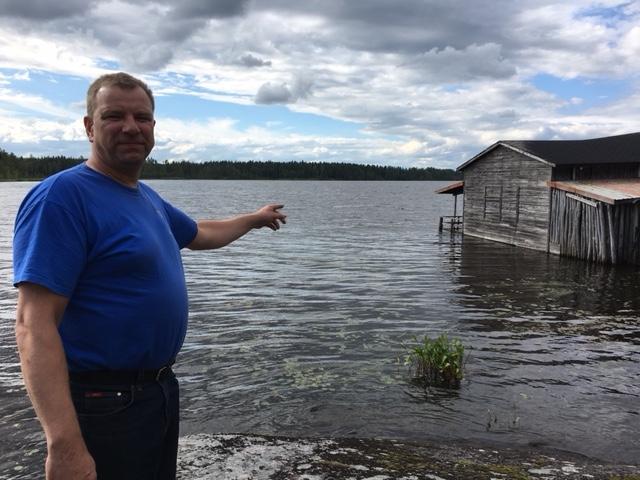 Marko Vainionpää osoittaa Aulavan huvikeskuksen rannassa sijaitsevaa latoa, jossa oli takavuosina yökerho. Nyt rakennus on veden vallassa.