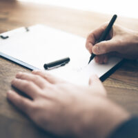 Henkilö kirjoittaa paperille