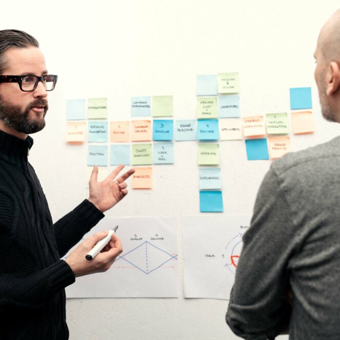 Kaksi miestä suunnittelemassa liiketoimintaa tarralappujen kanssa.