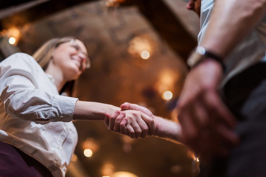 Yrittäjä ja uusi työntekijä kättelevät, toinen hymyilee, kuva alaviistosta.