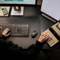 Verkkomyyntioppaan kansikuvassa yrittäjä istuu tietokoneen ääressä kädet näppäimistöllä ja laskukoneella.