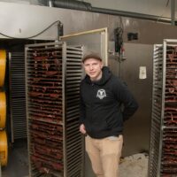 Timo Lahti eli Kuivalihakundi seisoo tuotantotiloissaan kuivaliharullakoiden välissä