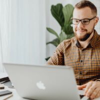 Mies istuu tietokoneella.