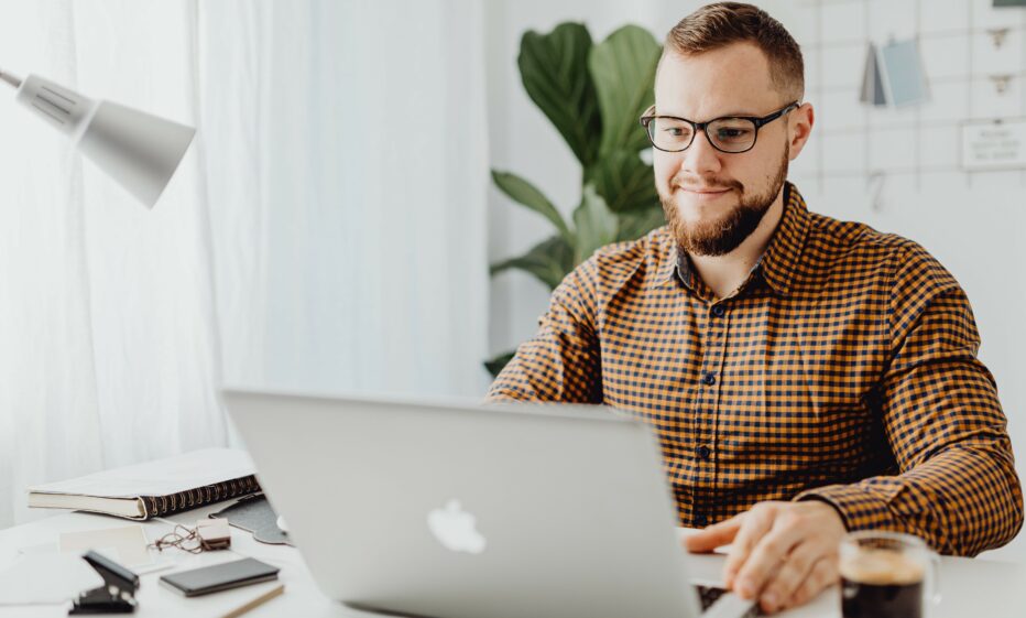 Mies istuu tietokoneella.