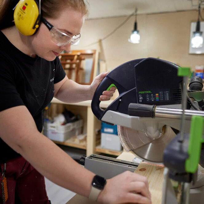 Henkilö sahaamassa puuta sirkkelillä.