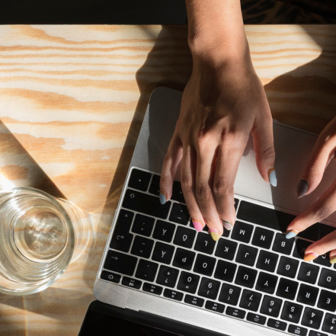 Naisen kädet kannettavan tietokoneen näppäimistöllä.