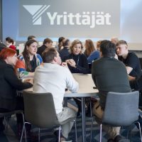 Ihmisiä tapahtumassa istumassa pöydän ympärillä
