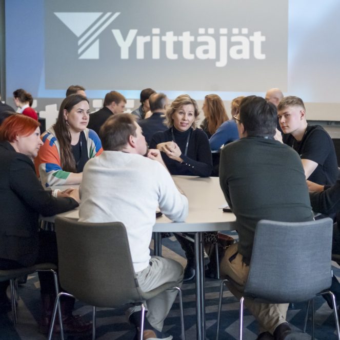 Ihmisiä tapahtumassa istumassa pöydän ympärillä