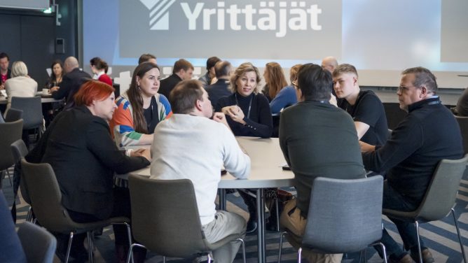 Ihmisiä tapahtumassa istumassa pöydän ympärillä