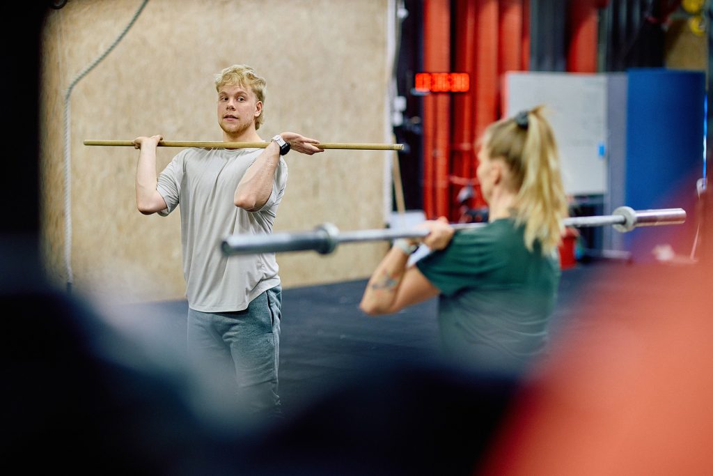 Kuntosaliyrittäjä ohjaa asiakasta kuntosalilla.